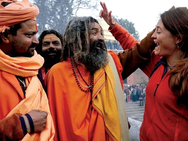 Une femme rit tandis qu’un sadhu lui touche la tête.